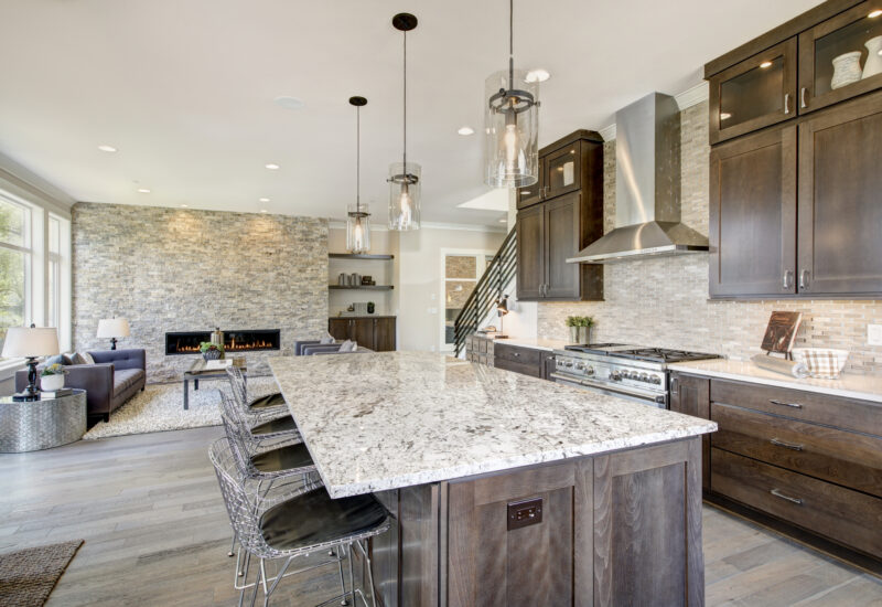 Luxury kitchen accented with large granite kitchen island, taupe tile backsplash, natural brown wood cabinets and high-end stainless steel appliances. Northwest, USA